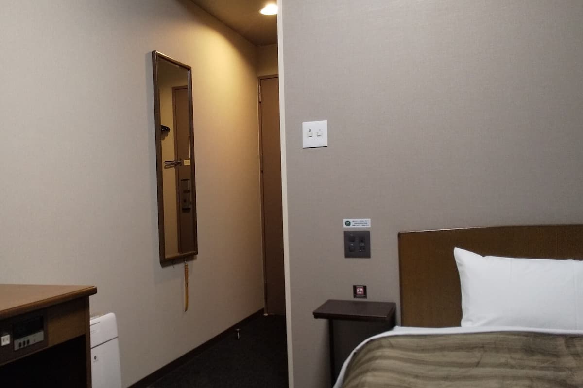 Ein Hotelzimmer mit einem Bett, einem Schreibtisch, einem Spiegel und einem kleinen Tisch.