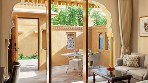 A room with a view of a garden through a decorative archway, a sofa, a table with a vase, and a chair. - Sawai Man Mahal, Jaipur (Jaipur)