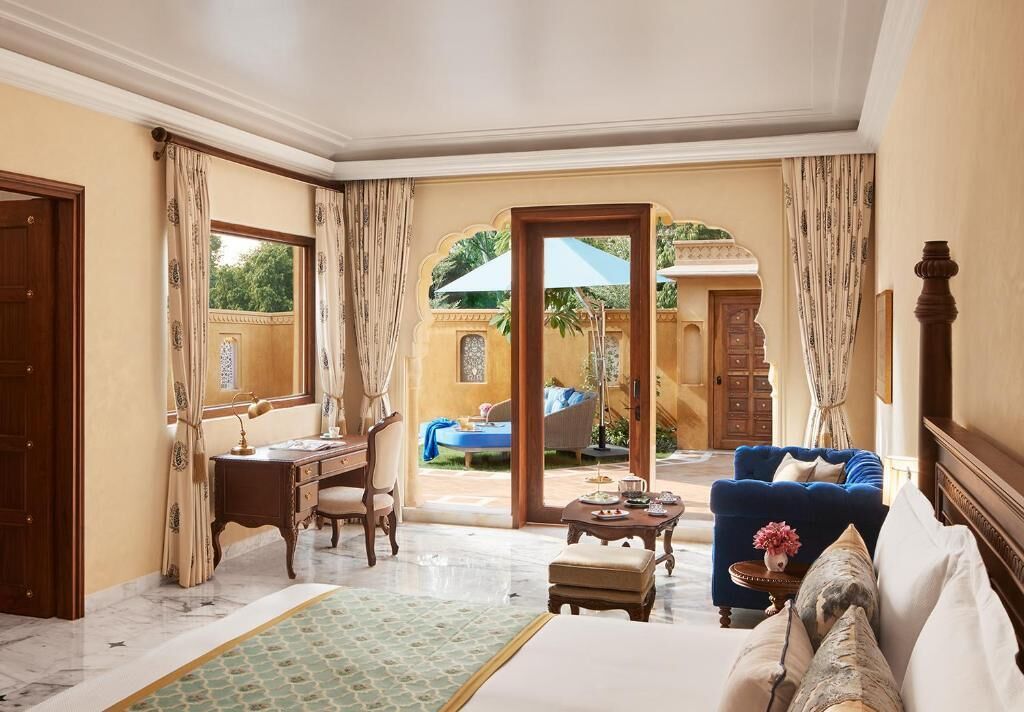 Une chambre d’hôtel comprenant un lit, un bureau, une chaise, un canapé et donnant sur une piscine extérieure.