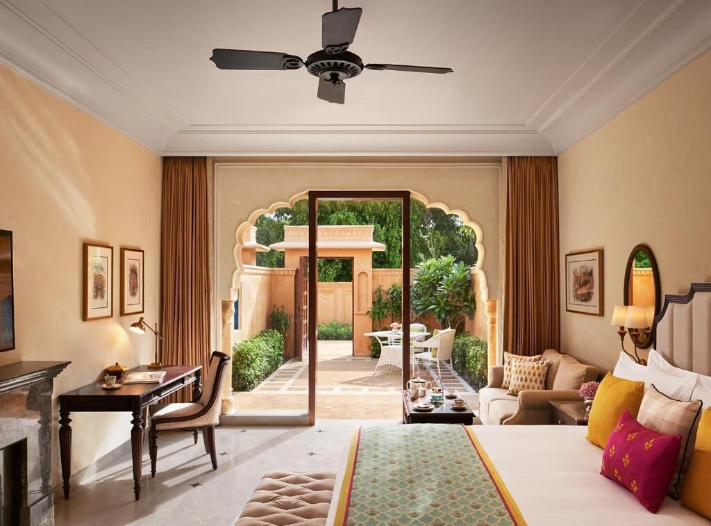Une chambre d’hôtel avec un lit, un bureau, une chaise et une vue sur une cour intérieure.