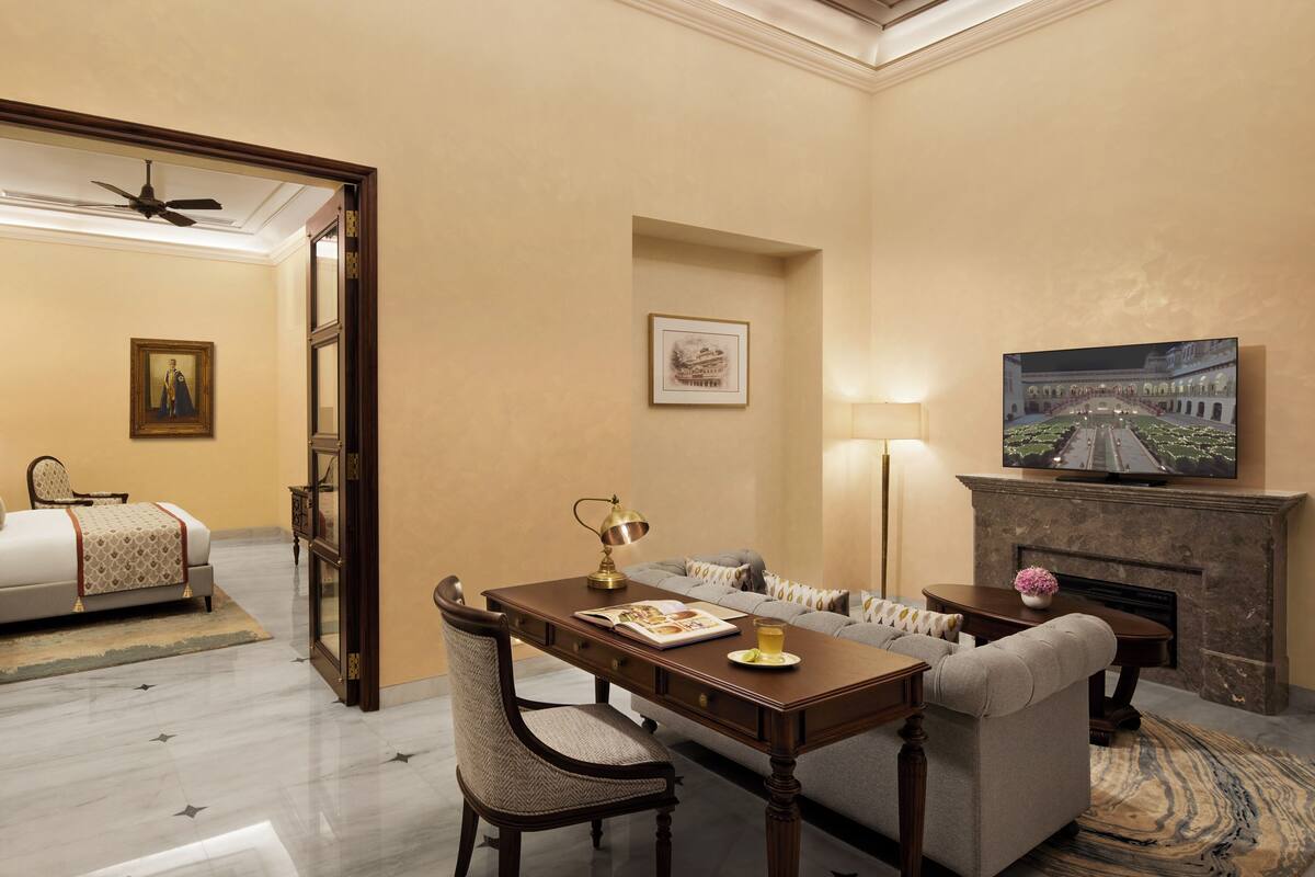 A hotel room with a dining area, a fireplace, and a bed.