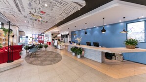 Un espace d’accueil moderne avec un mur bleu, un comptoir d’accueil et un canapé rouge.