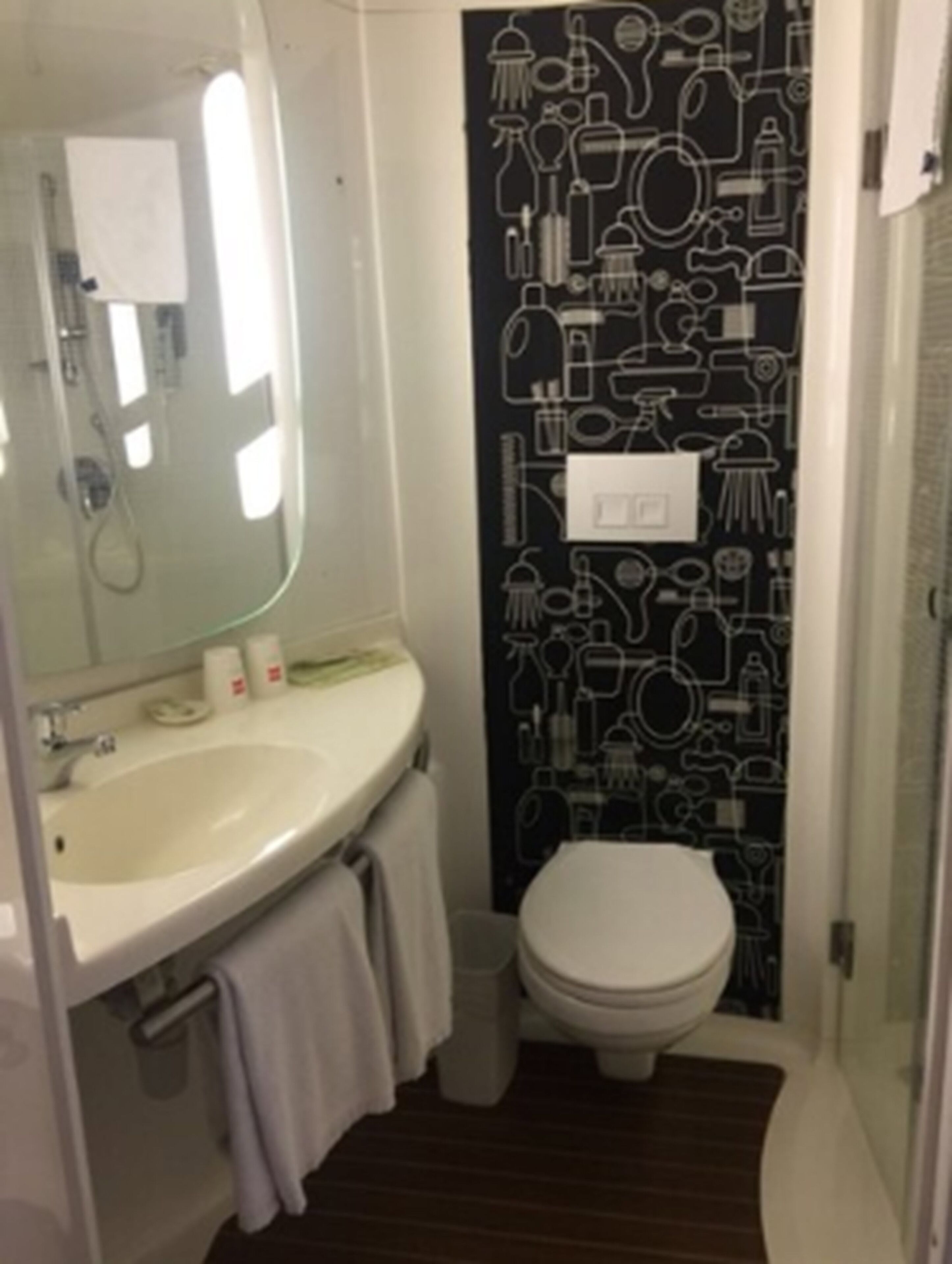 A small bathroom with a white sink, a mirror, a toilet, and a shower.