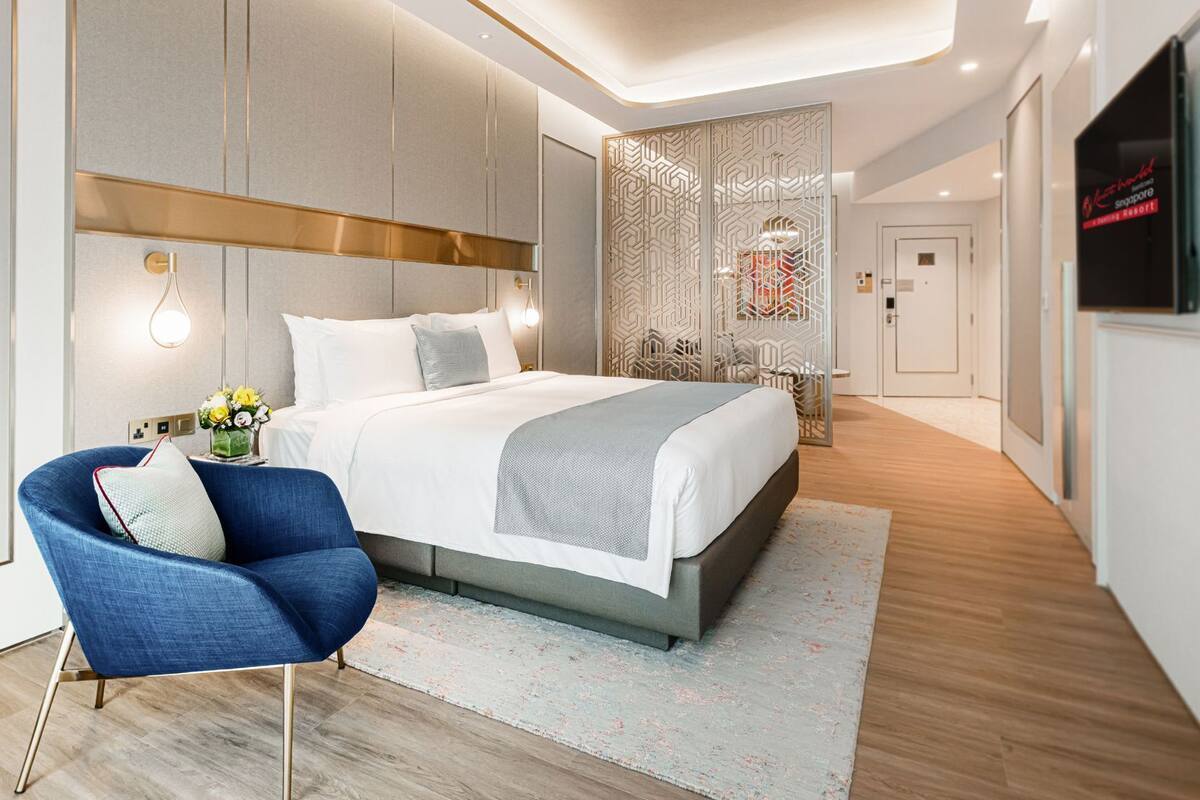 A modern bedroom with a large bed, a blue chair, and a decorative partition.