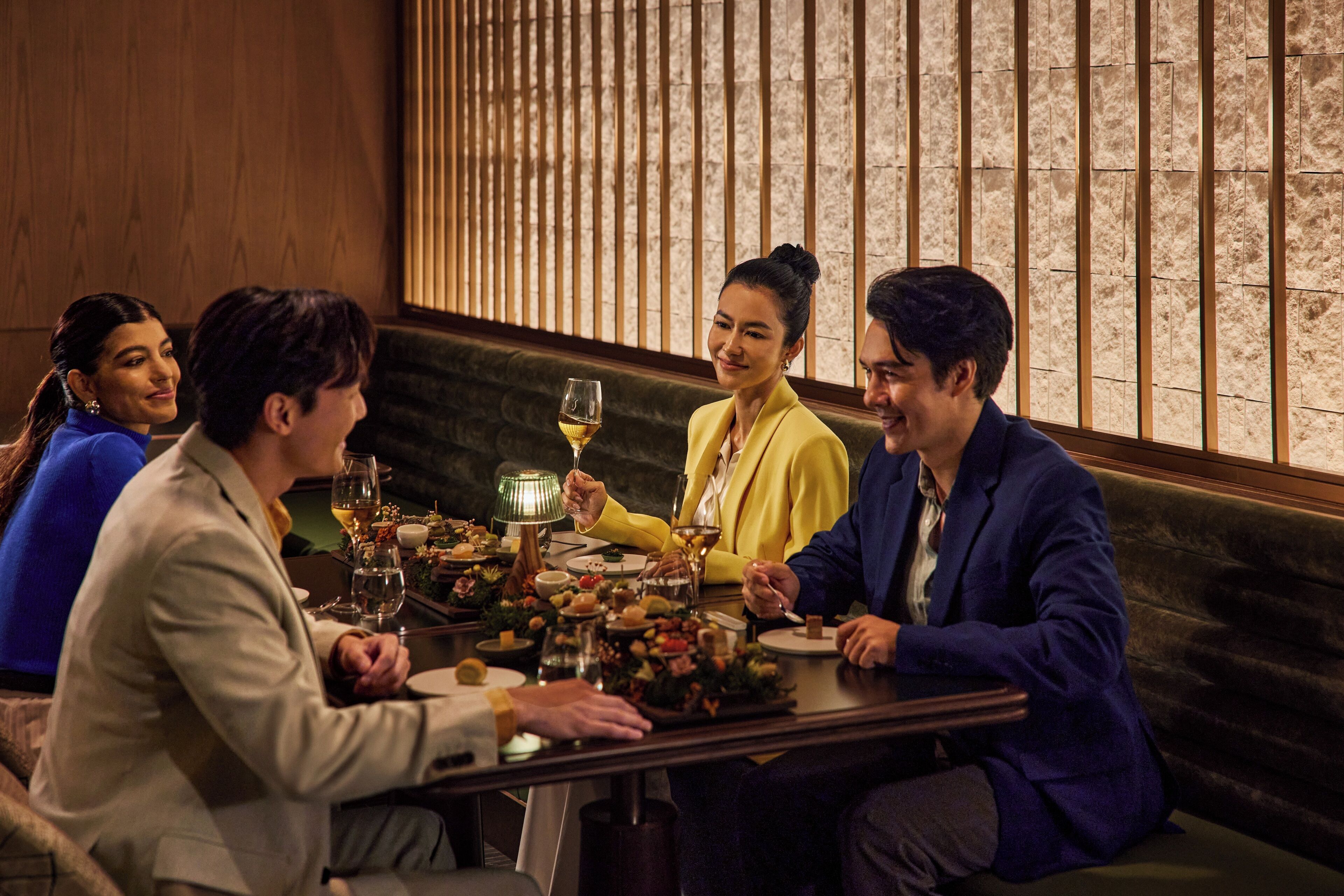 A group of people dining at a table with a candle, wine glasses, and a decorative centerpiece.