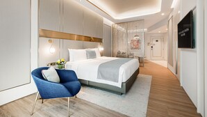 Ein modernes Hotelzimmer mit einem großen Bett, einem blauen Sessel und einem dekorativen Raumteiler.