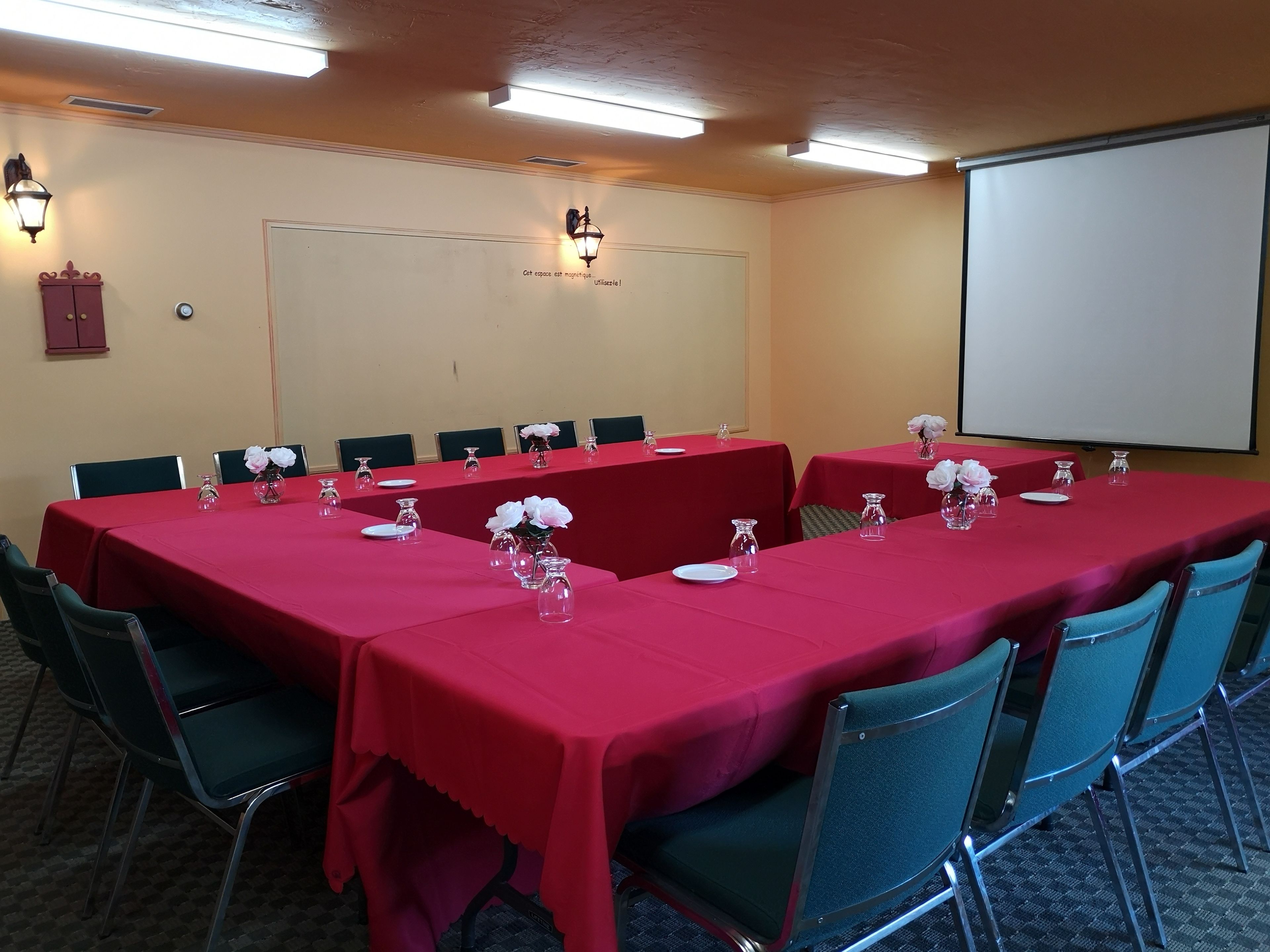A conference room with red tables, chairs, and floral centerpieces.