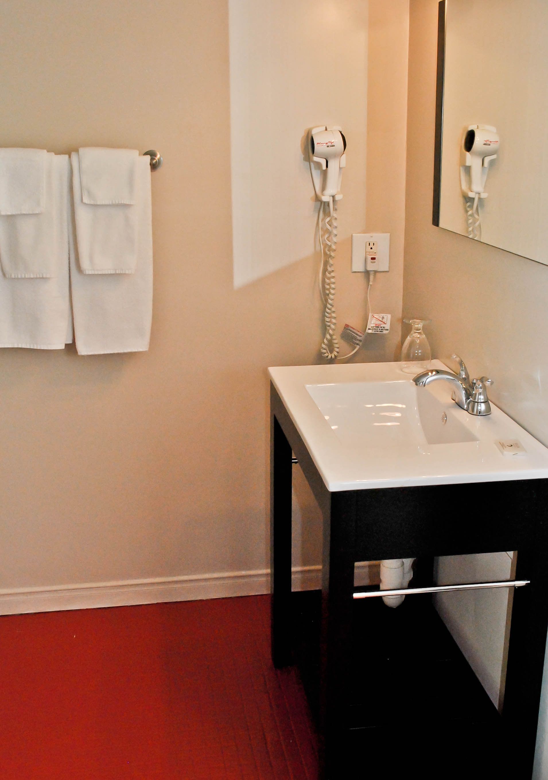 A bathroom with a white sink, a mirror, a hairdryer, and a towel rack.