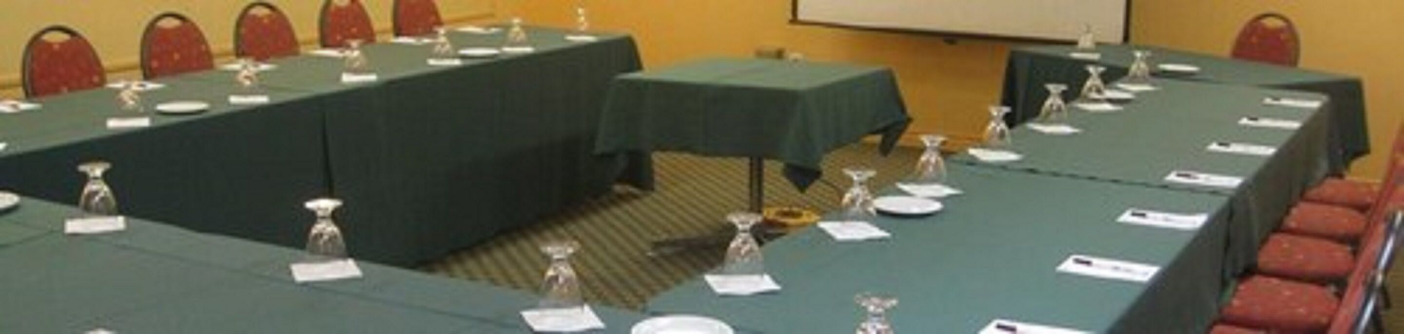 Une salle de conférence avec de longues tables, des plaques nominatives et des verres d’eau.