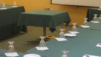Une salle de conférence avec de longues tables, des plaques nominatives et des verres d’eau.