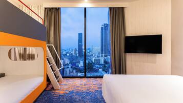 Quarto de hotel com vista para a cidade, uma cama, um sofá, uma televisão e uma escada.