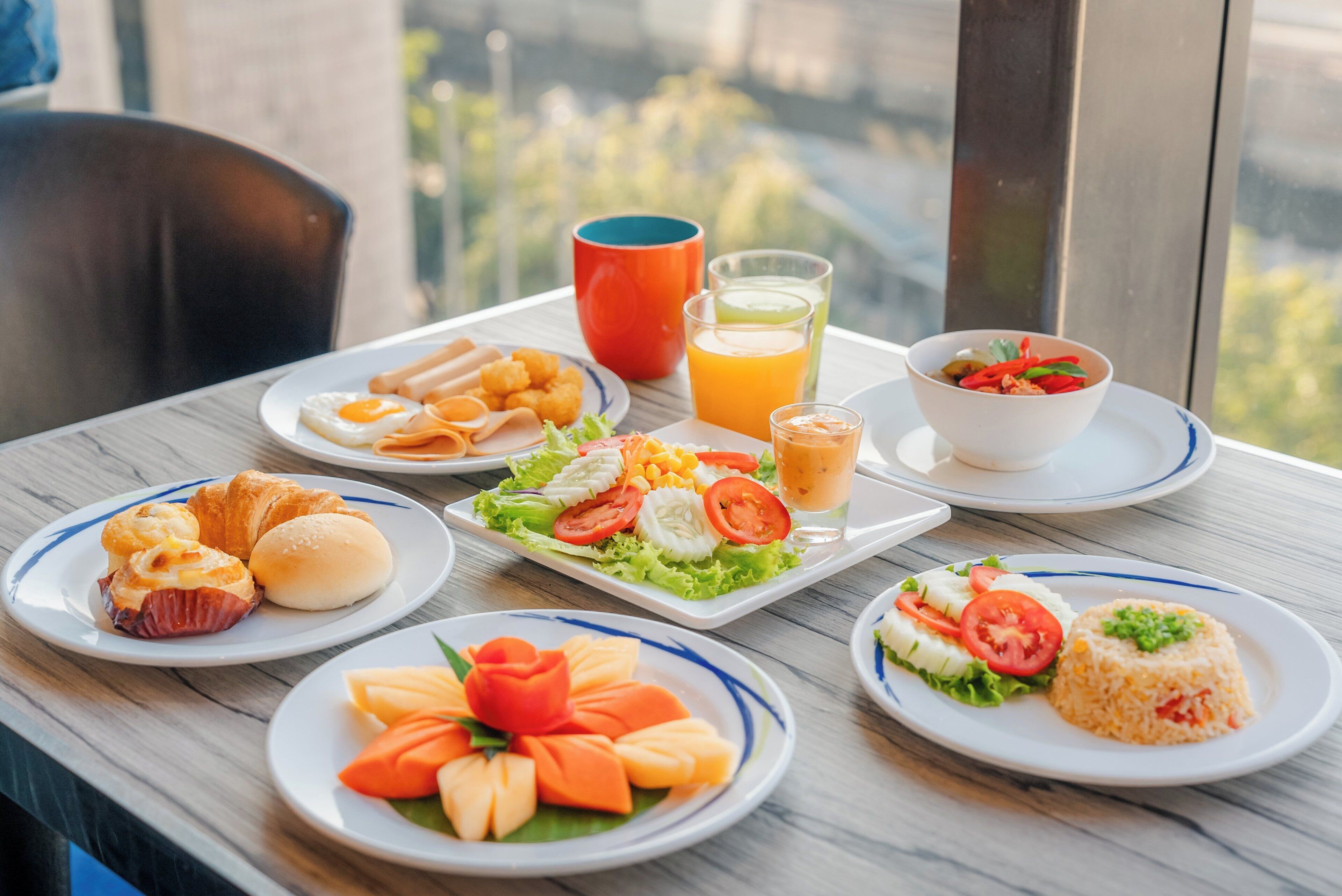 A table with various breakfast items including croissants, a fruit salad, and a bowl of soup.