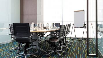 Un salón de conferencias con una gran mesa, varias sillas, una pizarra y botellas de agua.