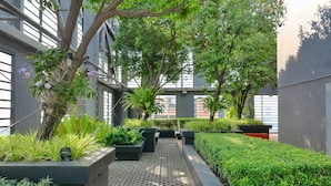 A modern outdoor area with a pathway, planters, and trees. - Holiday Inn Express Bangkok Siam by IHG (Bangkok)
