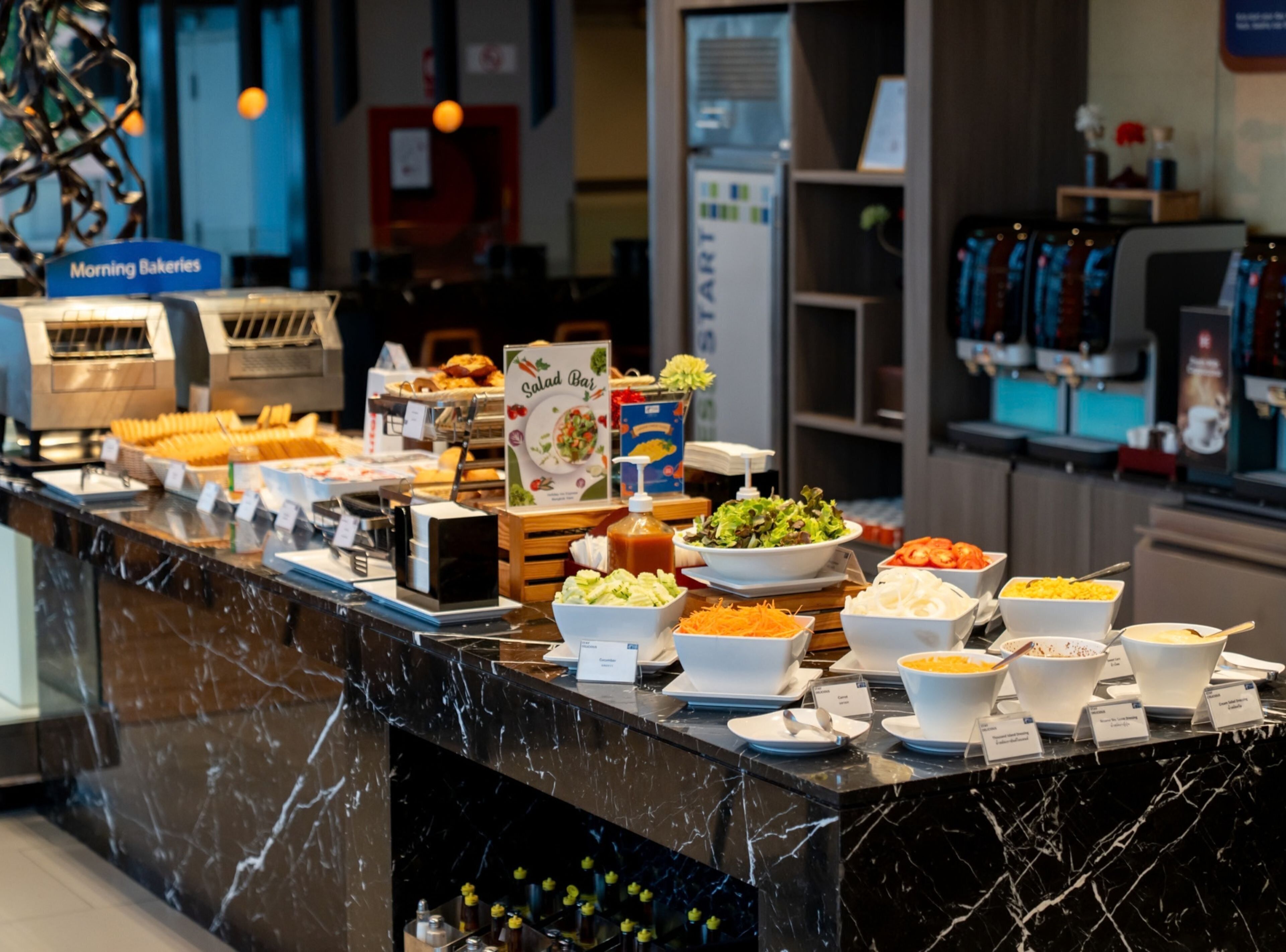 A buffet with various food options, a coffee machine, and a sign for 'Morning Bakeries'.