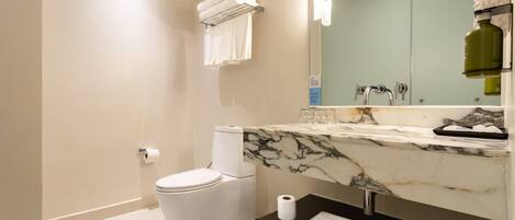 A modern bathroom with a toilet, a marble sink, a towel rack, and a mirror.