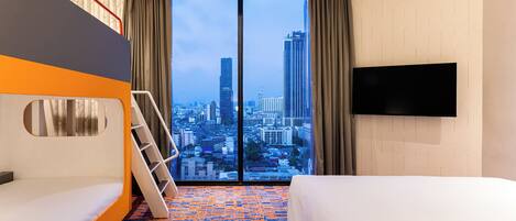 Habitación de hotel con vista a la ciudad, una litera, un televisor de pantalla plana y piso alfombrado.