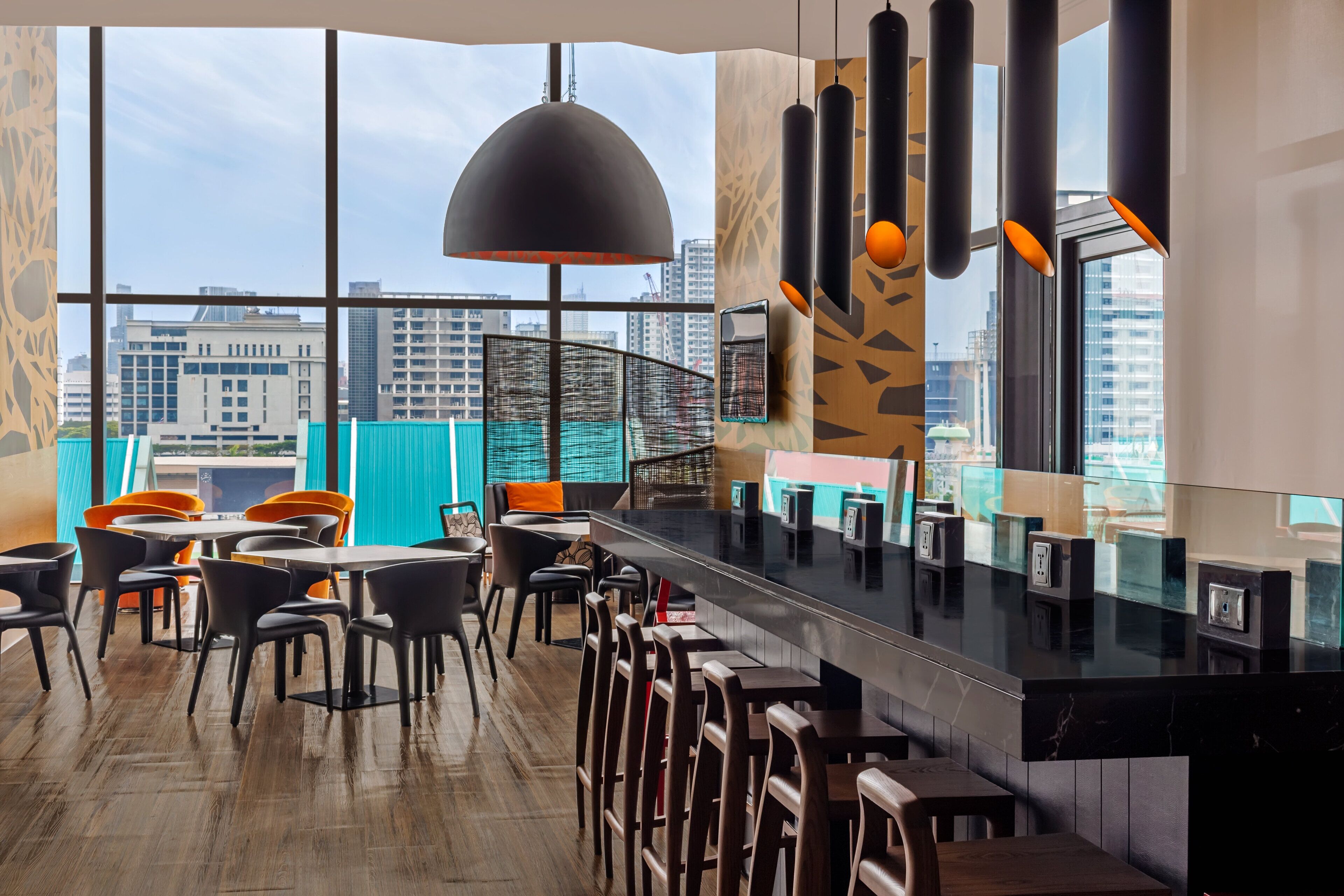 A modern bar area with high ceilings, large windows, and a view of the city skyline.