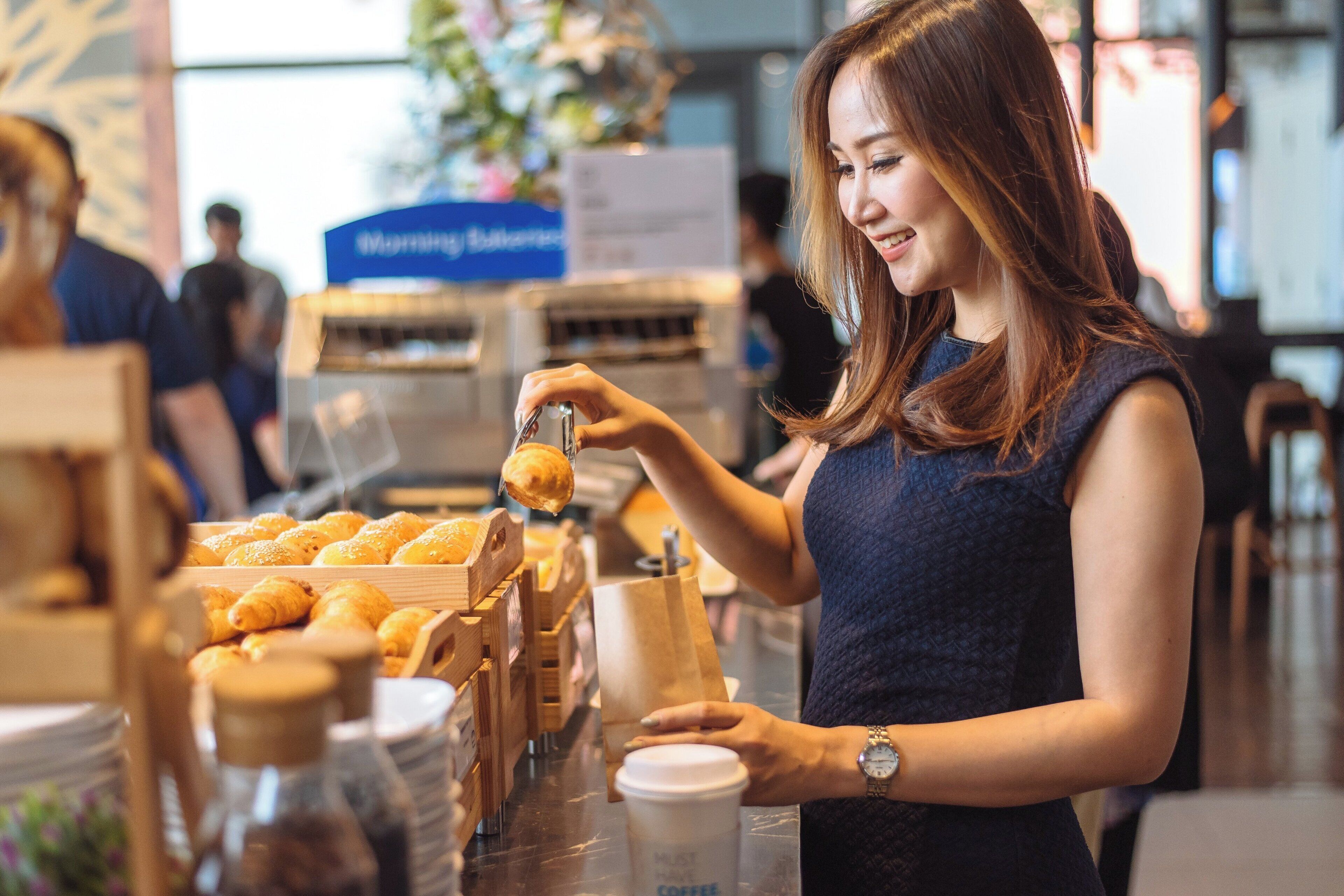 A person preparing food in a bakery setting with bread displayed in wooden crates.