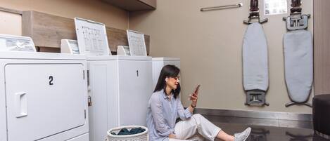 A laundry room with numbered cabinets, a basket, and ironing equipment.