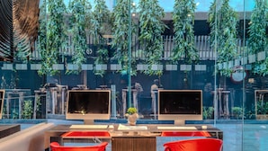 A modern indoor space with two computer monitors, a wooden table, and red chairs. - Holiday Inn Express Bangkok Siam by IHG (Bangkok)