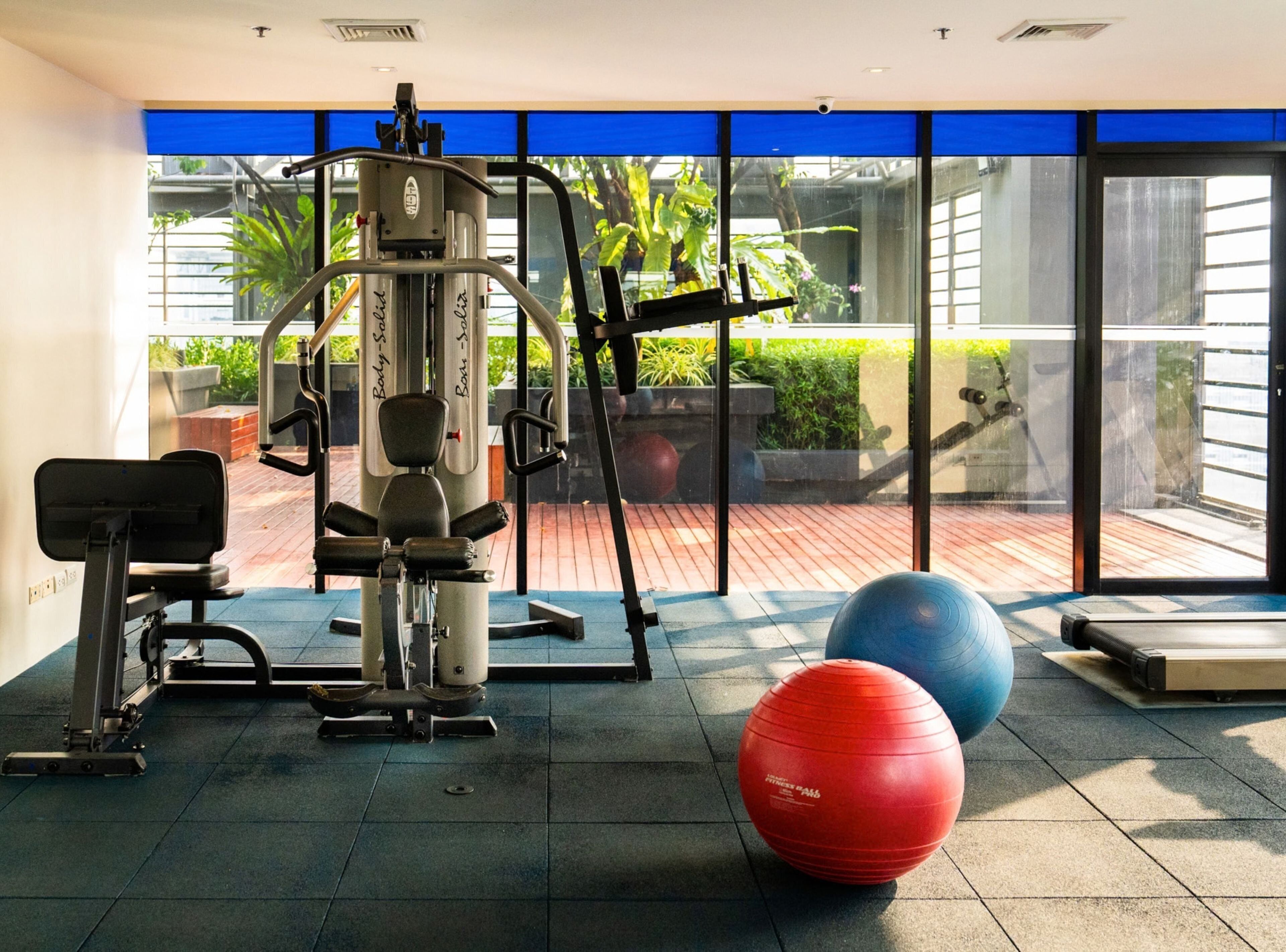 A gym with exercise equipment, a blue exercise ball, and a red exercise ball.