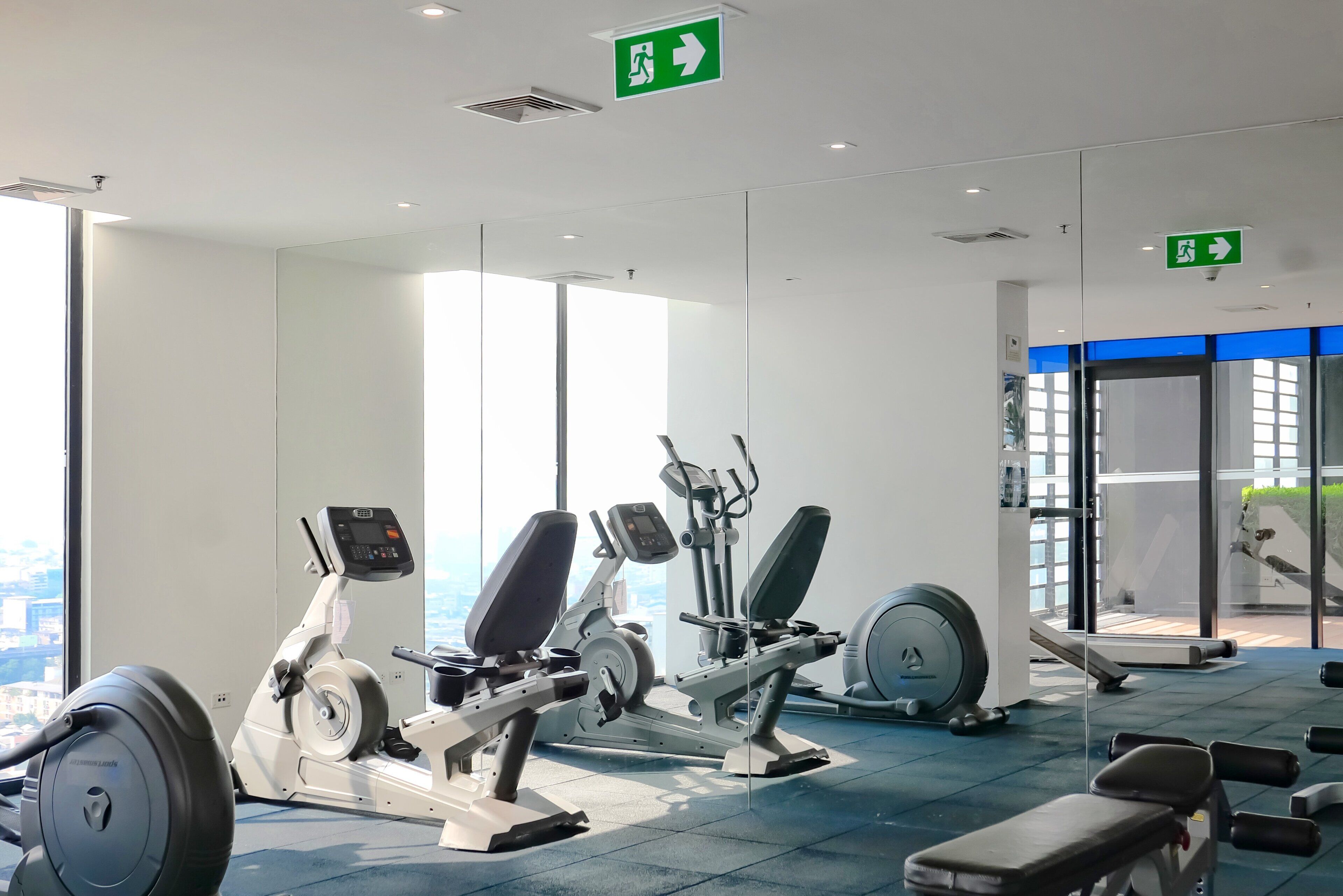 Une salle de sport équipée de machines de cardio, de bancs et d’un tapis de course.