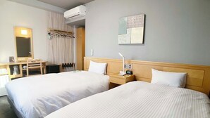 Une chambre d’hôtel avec deux lits, un bureau avec une chaise, un miroir, un climatiseur et une œuvre d’art accrochée au mur.
