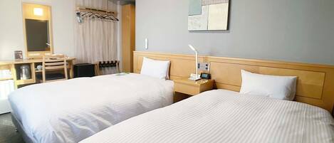 A hotel room with two beds, a desk with a chair, a mirror, an air conditioner, and a wall-mounted artwork.