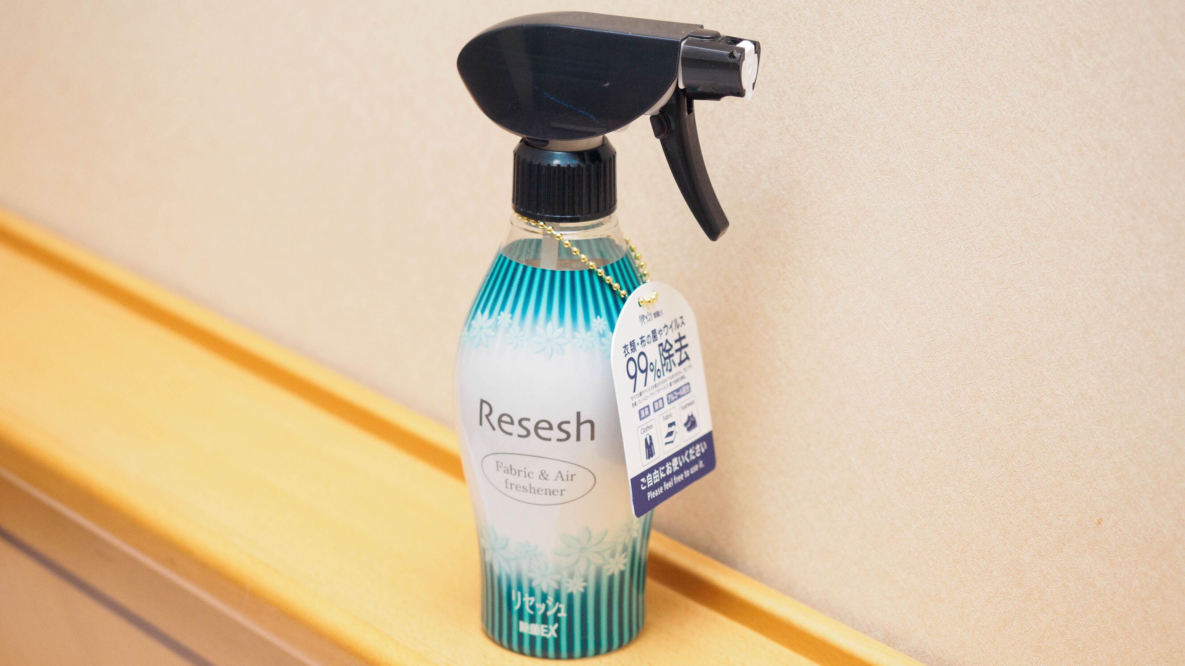 A bottle of Reeshe brand fabric & air freshener on a wooden surface.