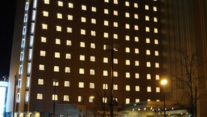 Een hoog hotelgebouw met een neonbord bovenaan.