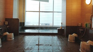 Een badkamer met een groot raam, een bad en een wastafel.