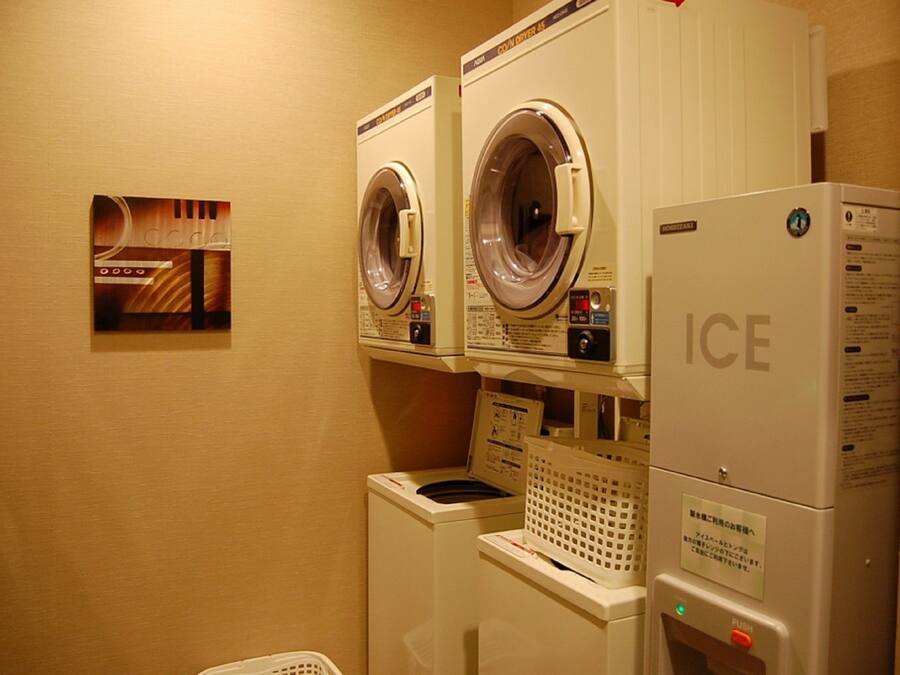 A laundry area with two front-loading washing machines and a dryer stacked on top of each other.