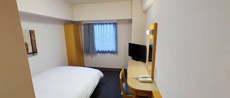 Habitación de hotel con cama, escritorio con computadora, silla, televisor y ventana con cortinas.