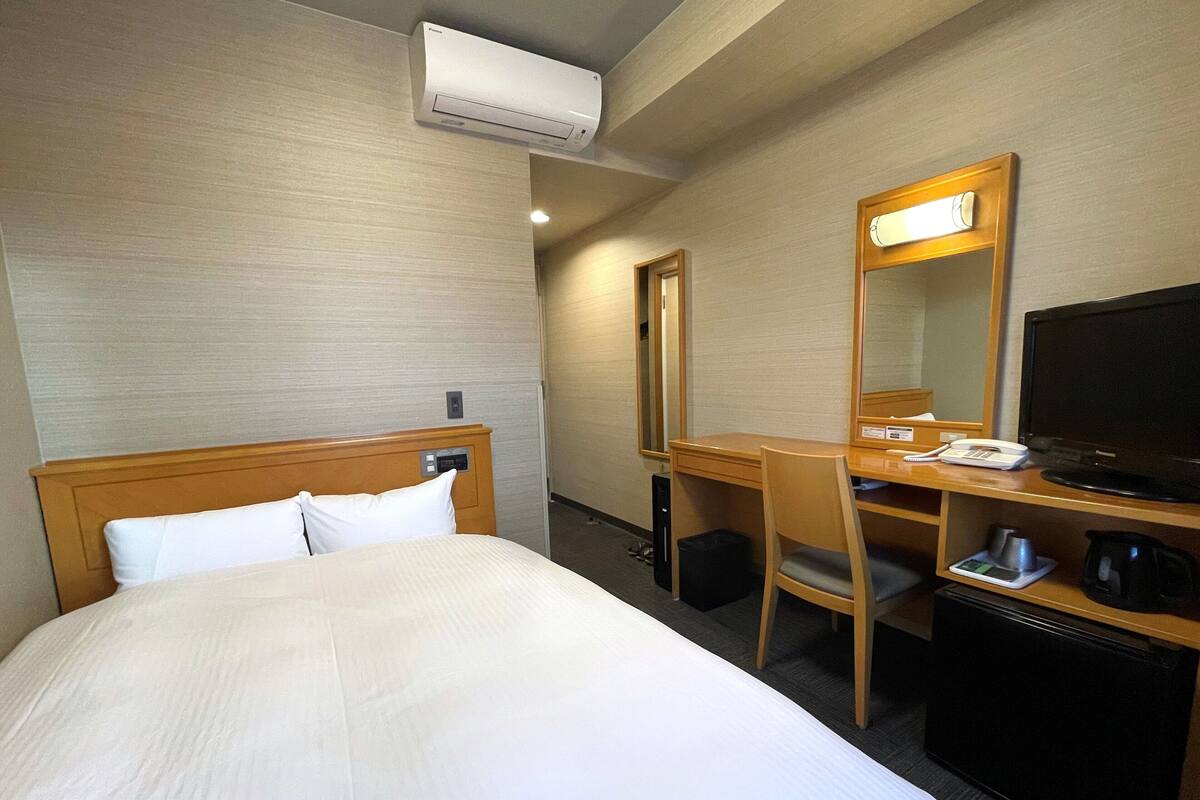 Une chambre d’hôtel équipée d’un lit, d’un bureau, d’une chaise, d’une télévision et d’un appareil de climatisation.