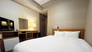 Une chambre d’hôtel avec un grand lit, un bureau avec une lampe, une télévision et un minibar.