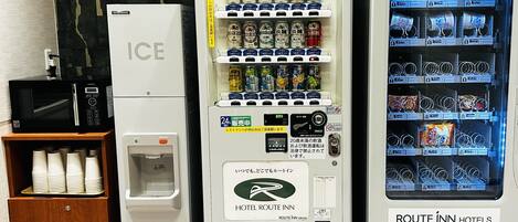 A vending machine with multiple beverage options, a microwave, and a water dispenser.