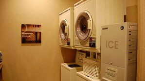 A laundry area with two front-loading washing machines and a dryer stacked on top of each other. - Hotel Route-Inn Yukuhashi (Yukuhashi)