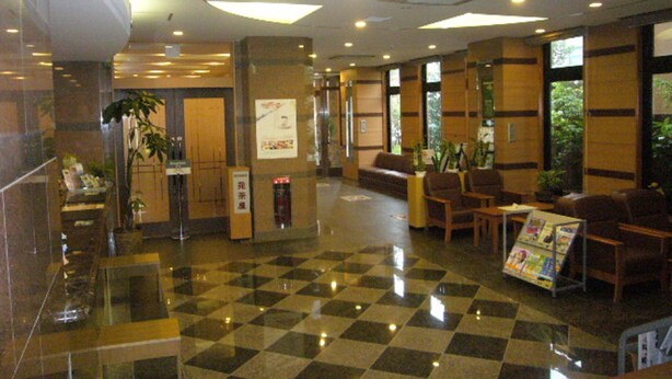A lobby with a checkered floor, seating area, and a reception desk. - Hotel Route-Inn Yukuhashi (Yukuhashi)