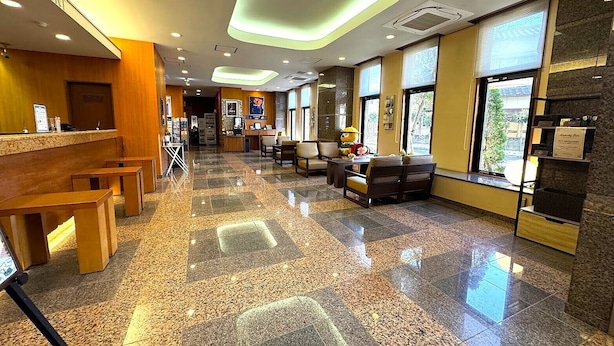 A hotel lobby with a reception desk, seating area, and large windows. - Hotel Route-Inn Isahaya Inter (Isahaya)