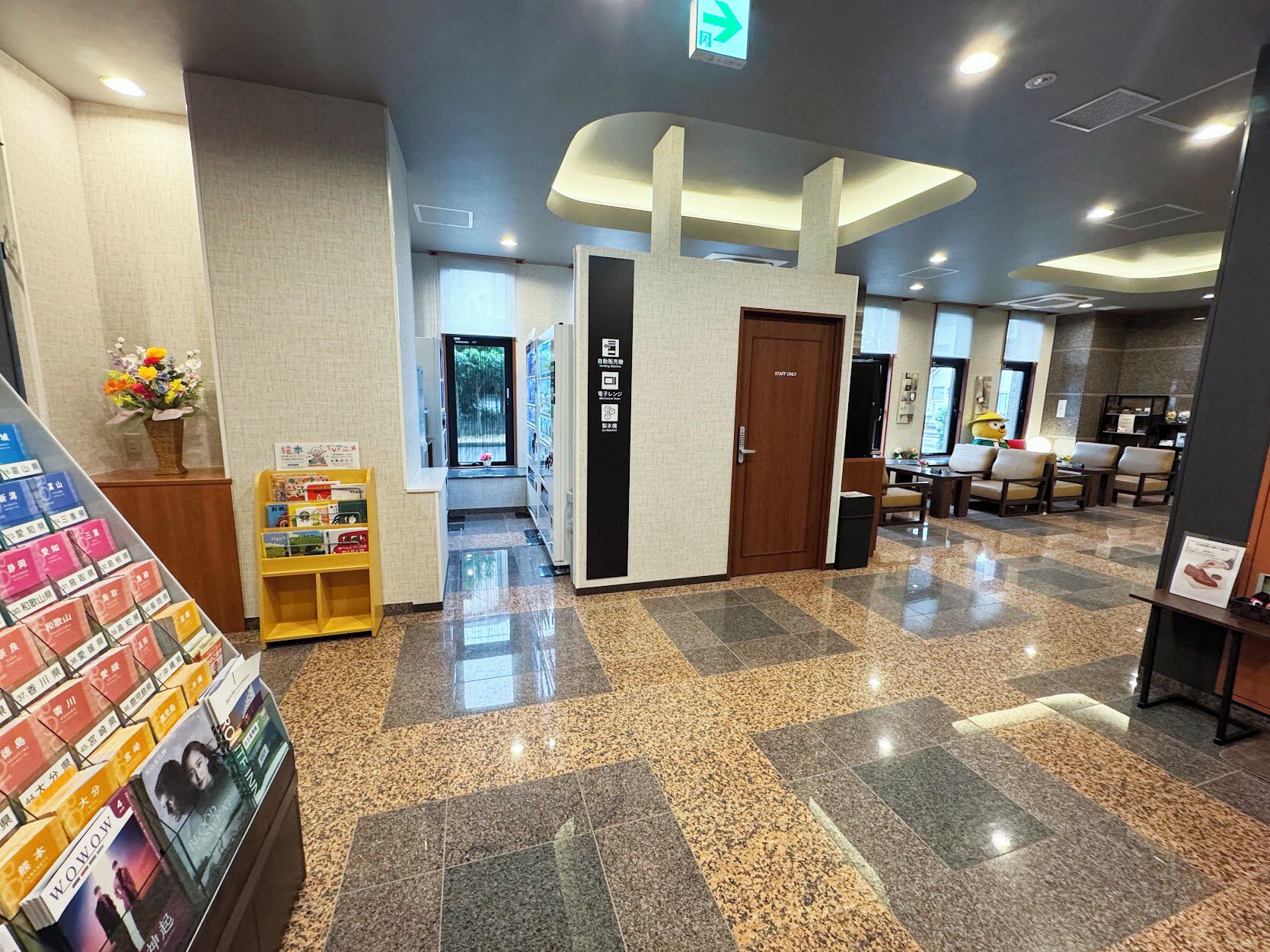 A hotel lobby with a reception desk, a 'Staff Only' door, a vending machine, and a seating area with chairs.