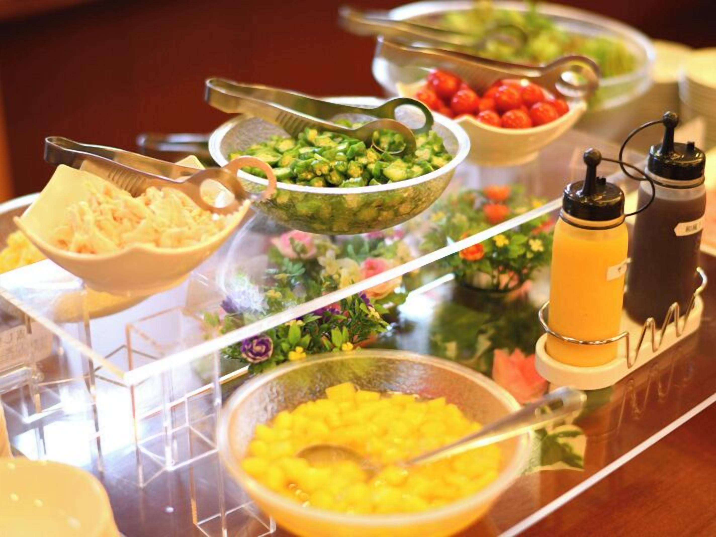 Un bufé con diversos platos, incluyendo ensaladas, frutas y un dispensador de bebidas.
