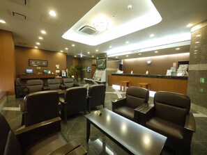 Welcome to our hotel lobby, featuring a reception desk, comfortable seating areas and a potted plant.