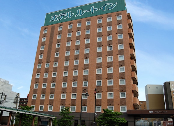 A multi-story hotel building with a green sign at the top.