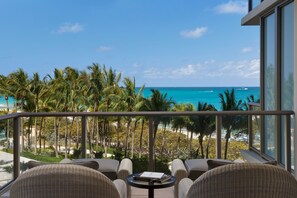 A balcony with wicker furniture, a small table, and a view of the ocean and palm trees. - The St. Regis Bal Harbour Resort (Bal Harbour)