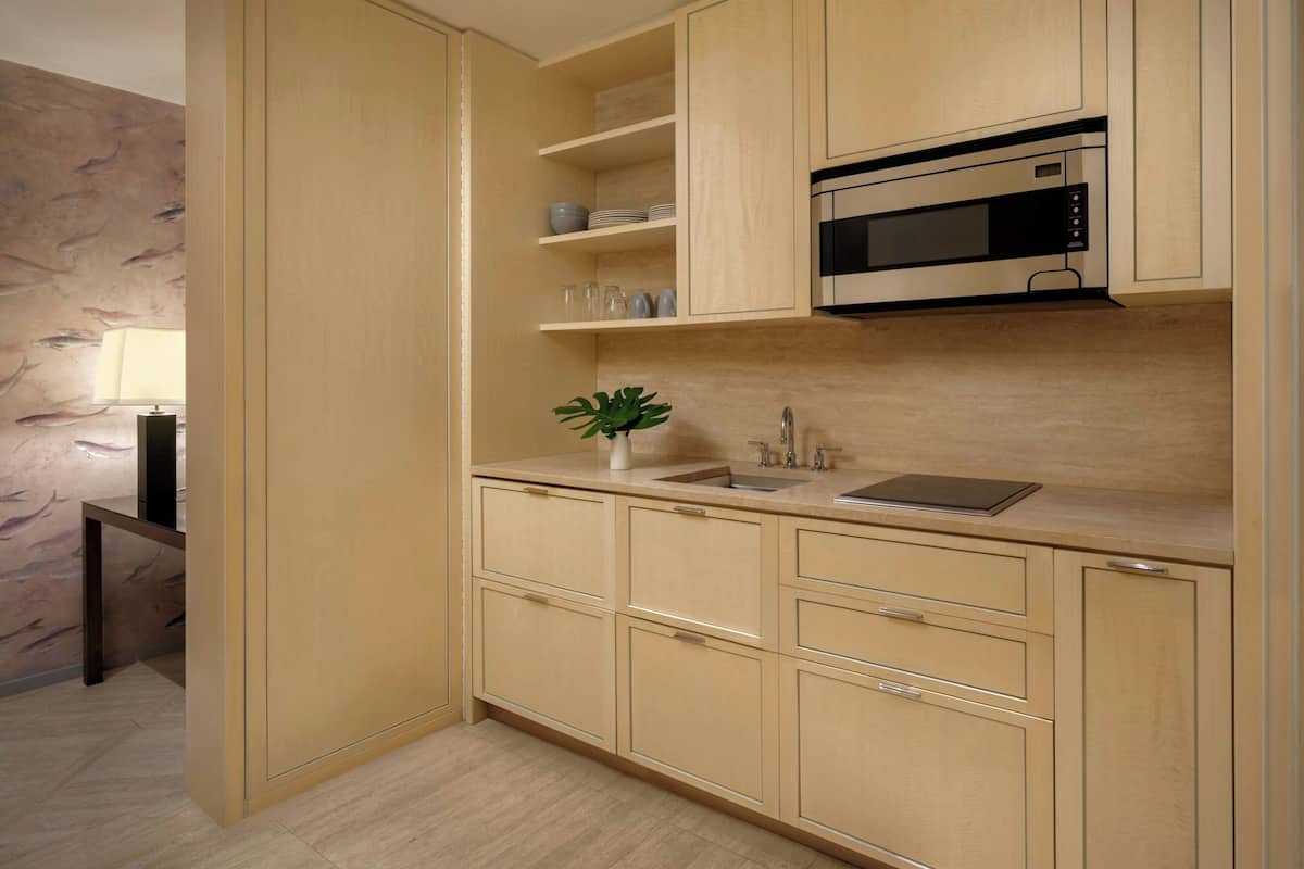 A kitchen with wooden cabinets, a microwave, a sink, and a plant on the counter.