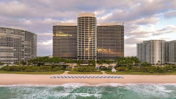 Um hotel na praia com vários edifícios altos, uma praia de areia e ondas do oceano.