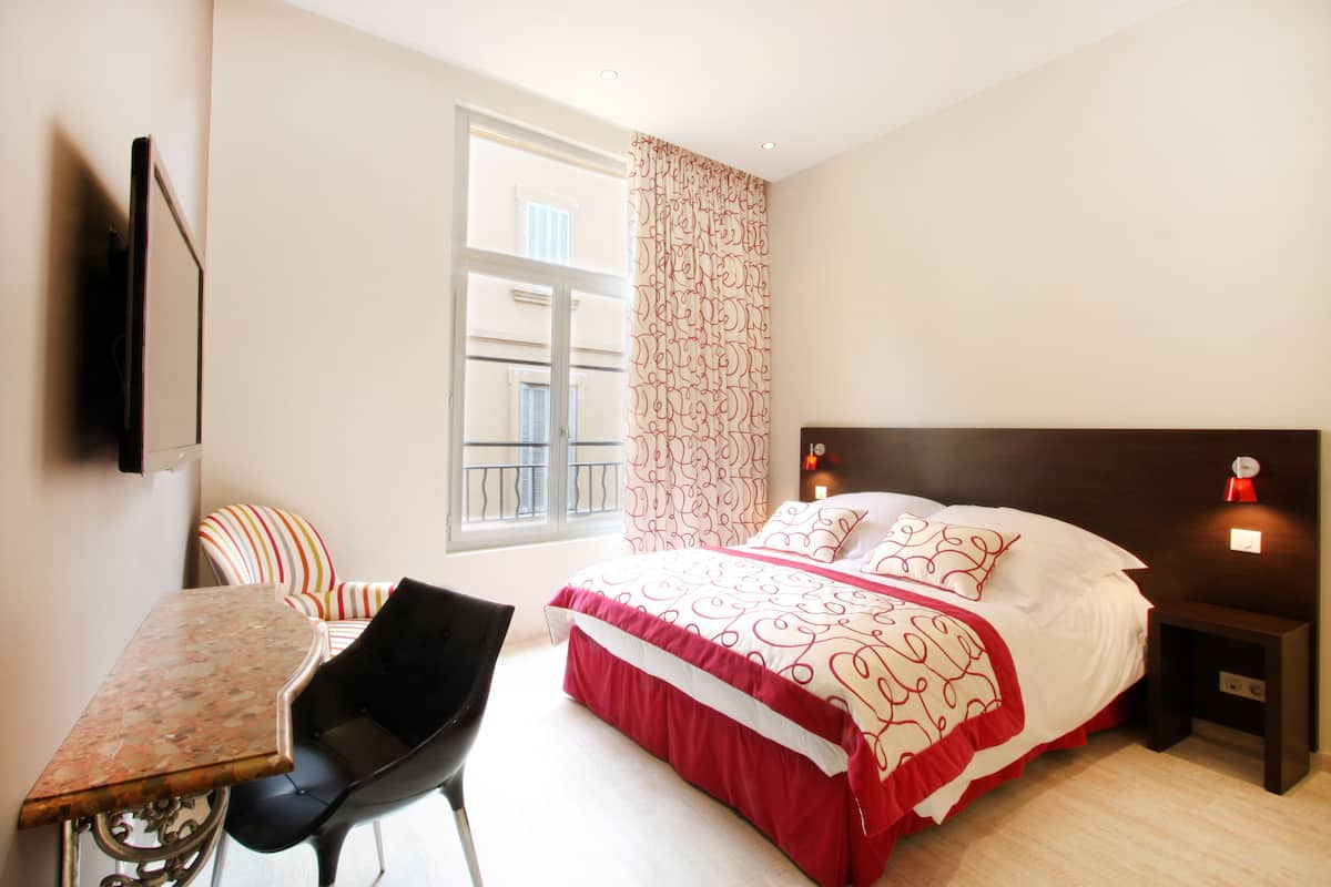 Une chambre à coucher avec un lit, un bureau, une chaise et une fenêtre avec des rideaux.