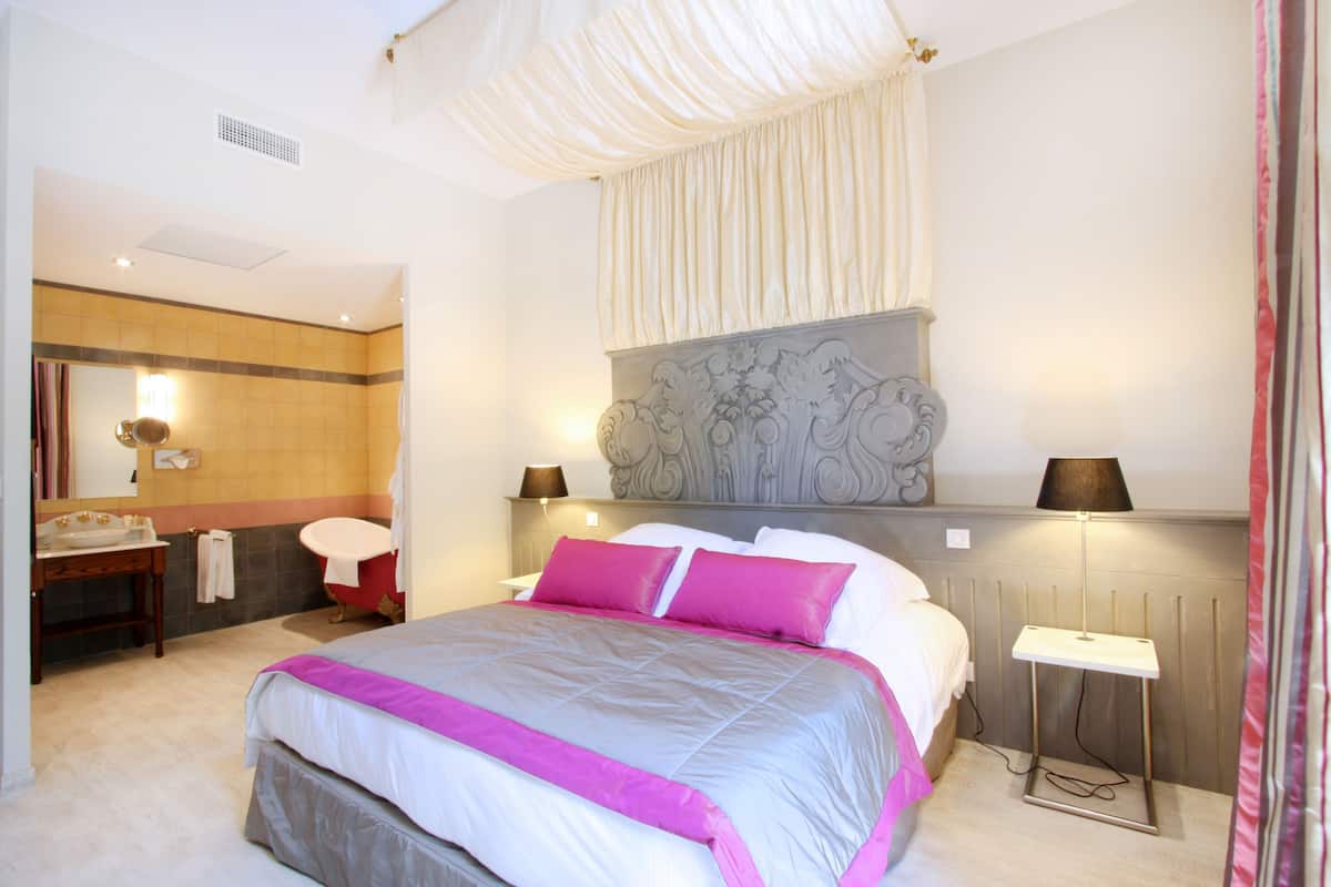 Une chambre à coucher moderne avec un grand lit, des lampes de chevet, une coiffeuse avec un miroir et une tête de lit décorative.