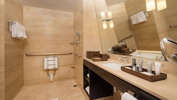 A modern bathroom with a walk-in shower, a vanity with a mirror, and a sink.